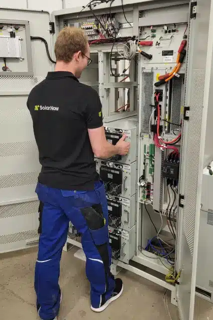 Mitarbeiter von SolarNow installiert einen Gewerbespeicher für Unternehmen in einem Energiesystem-Schaltschrank.