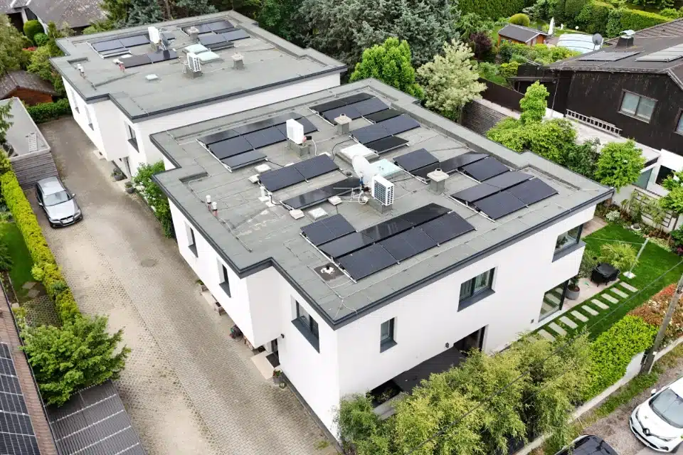 PV-Anlage auf Flachdach Wien Donaustadt auf zwei modernen weißen Wohnhäusern mit Flachdach-Aufständerung und Schotterung, installiert von SolarNow