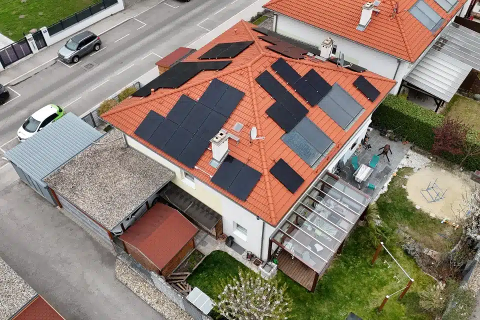 PV Anlage Schrägdach Wien Donaustadt auf einem Haus mit roten Ziegeln, einer Glasüberdachung auf der Terrasse und Garten, installiert von SolarNow