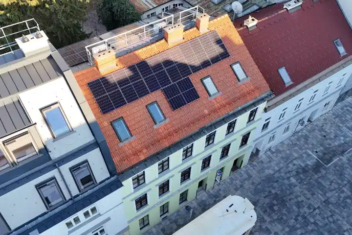 PV-Anlage auf einem Schrägdach in Wien Schutzzone, Währing. Solarpaneele auf rotem Ziegeldach eines mehrstöckigen Gebäudes.
