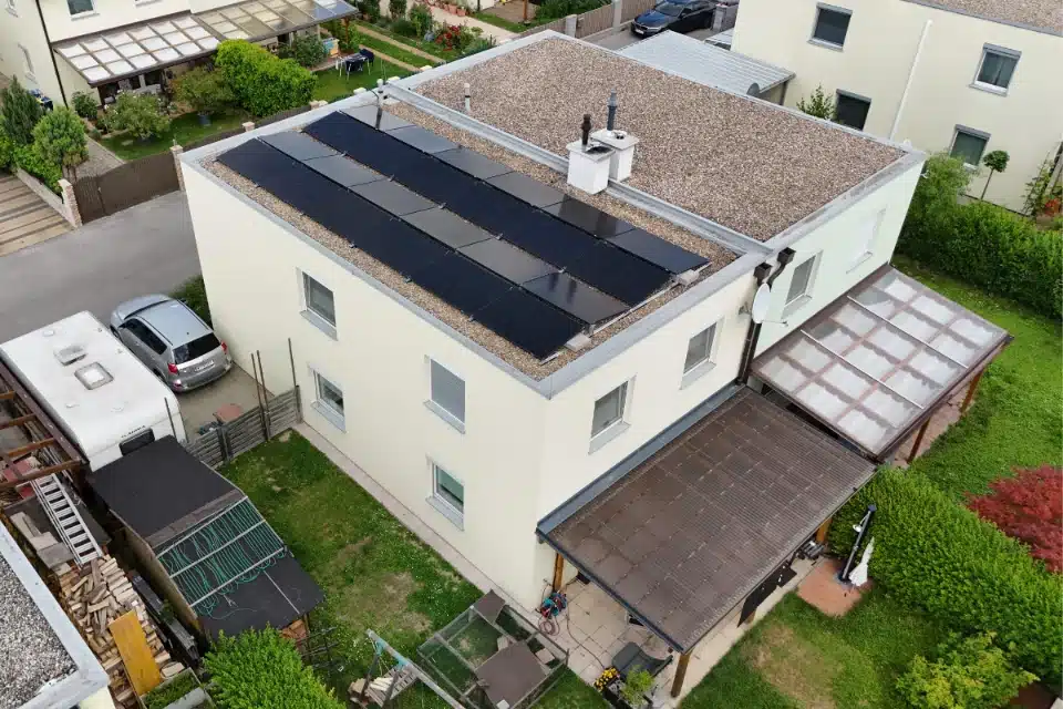 Photovoltaik auf Flachdach Wien Donaustadt SolarNow Anlage auf einem bekiesten Flachdach eines modernen Wohnhauses mit Terrasse, installiert von SolarNow