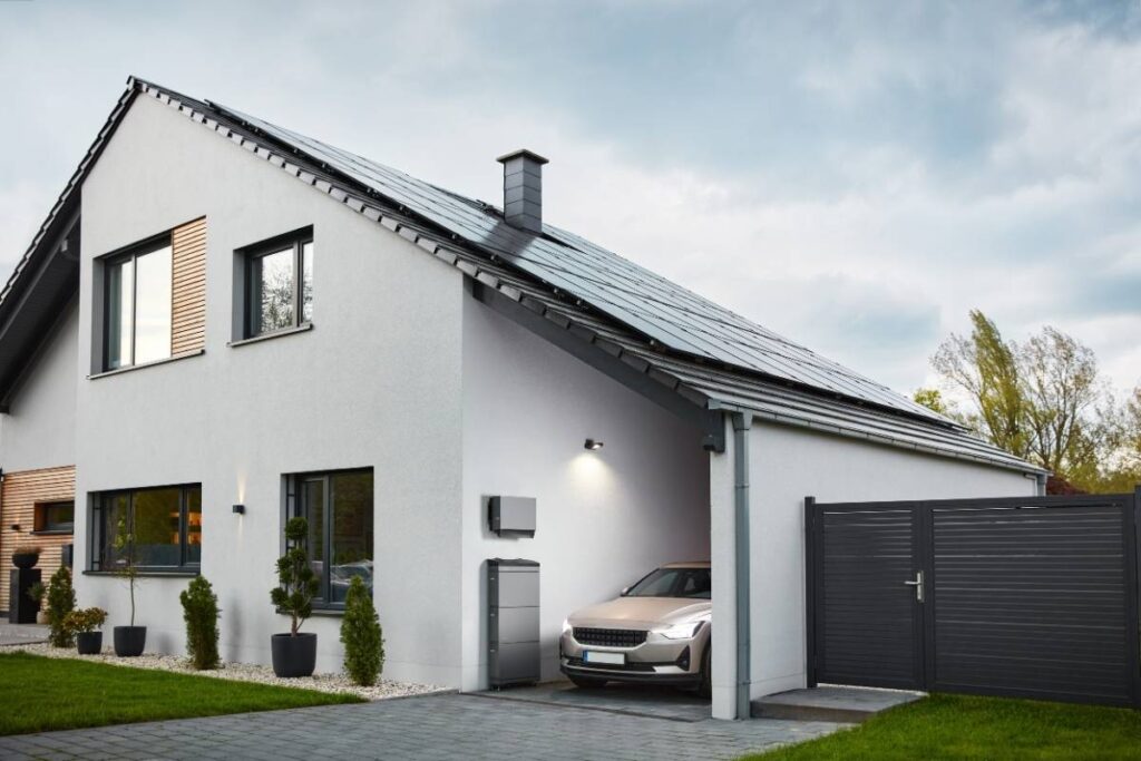 Modernes Einfamilienhaus mit Photovoltaikanlage auf dem Dach und Elektroauto in der Einfahrt.
